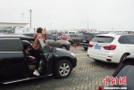 2月23日，海南海口新海港内，一位旅客拿出手机拍摄大批待渡车辆。　尹海明 摄 - 中新网海南频道