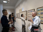 陈丕瑜向参观者讲述明信片的故事。尹海明 摄 - 中新网海南频道