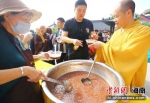 1月2日，三亚南山寺僧人为游客赠腊八粥。 景区供图 - 中新网海南频道