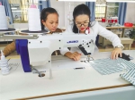 海南残服爱心服装厂负责人李王花在指导残疾员工缝纫技巧。 - 中新网海南频道