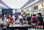 图为8月26日游客在三亚国际免税城内选购电子产品。　尹海明 摄 - 中新网海南频道