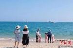 图为在天涯海角游览区，家长带着孩子在海边嬉浪。　游建行 摄 - 中新网海南频道