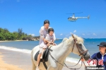 图为在天涯海角游览区，家长带着孩子在海边骑马。　游建行 摄 - 中新网海南频道