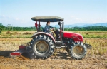 刘国锋驾驶拖拉机翻耕土地，为种植毛豆做准备。 武威 摄 - 中新网海南频道