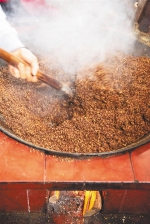 工人在翻炒油茶种仁，以土法热榨海南茶油。 - 中新网海南频道
